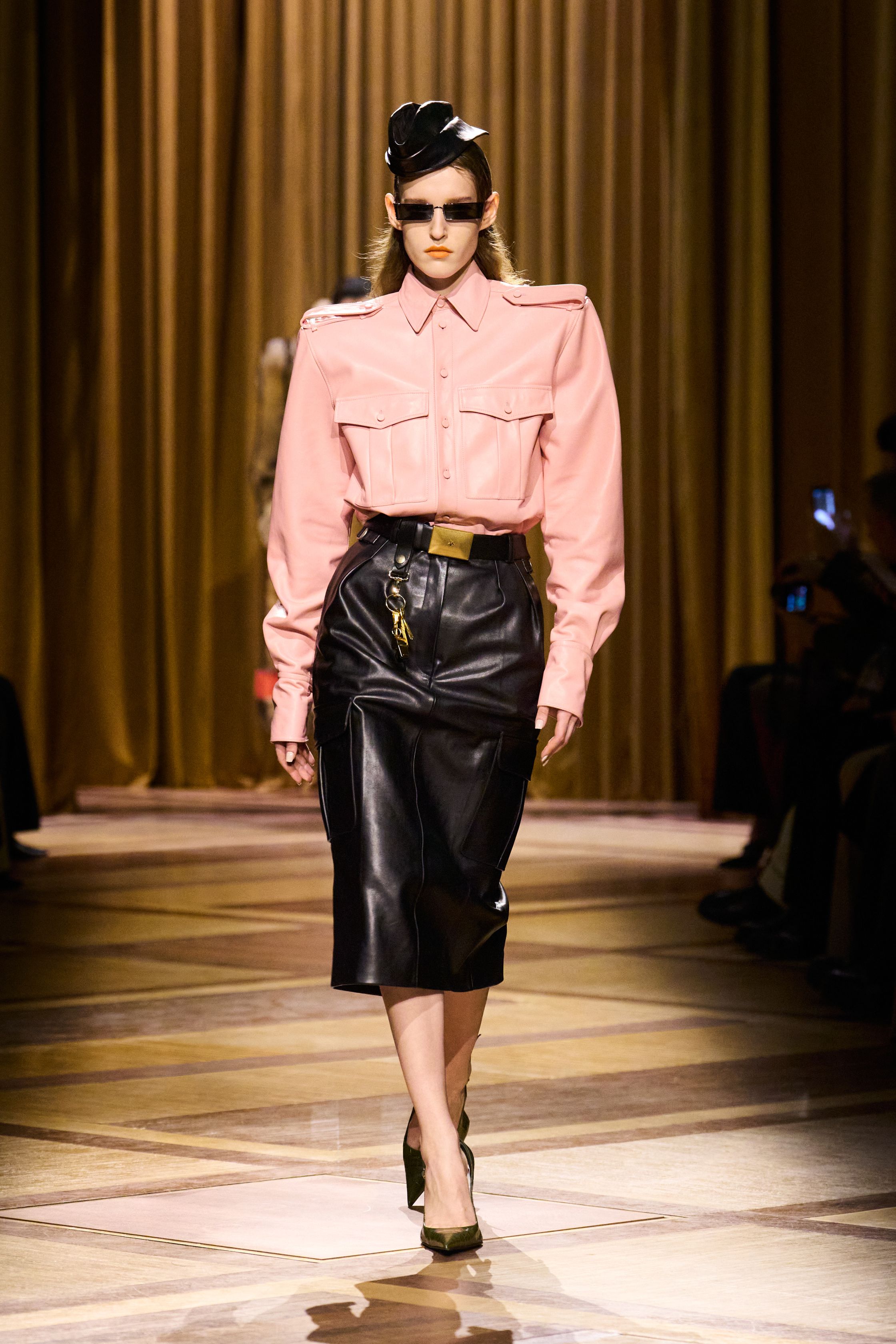 Mugler 本季继续强化品牌最核心的雕塑性感：极端肩线、收紧腰部与流畅长裤塑造出未来感女性轮廓。紫色权力套装、金属光泽衬衫和皮革裙装让整场秀既强势又华丽，仿佛科幻电影中的都市女主角-顽石频道趋势研究